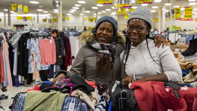 Two women smile while shopping in a department store.