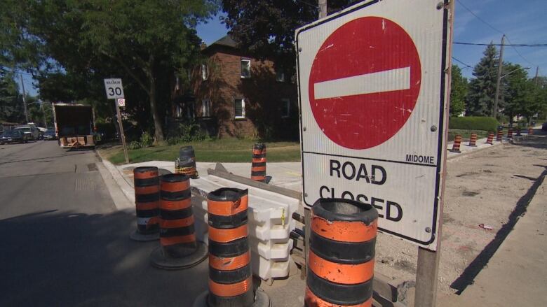 A 'Road Closed' sign stands alongside construction pilons to mark the construction zone on Glen Cedar Road.