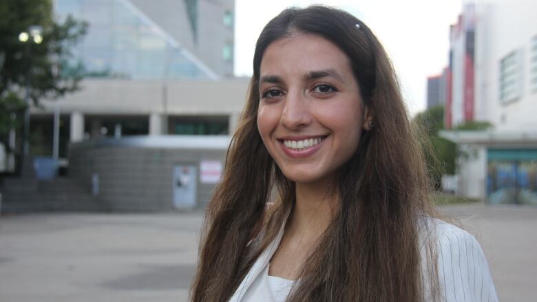 A smiling woman with brown hair and a white jacket.