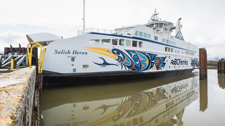 A ship with a painting of a heron, in Coast Salish art style, on the side of it. 