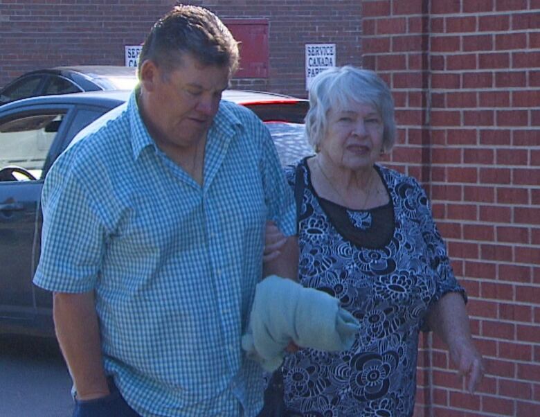 Lillian Thomey, 80, walks arm-in-arm with her son, Paul Thomey, to Harbour Grace provincial court one day in late June. 