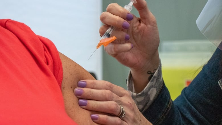 A person puts a needle in another person's arm