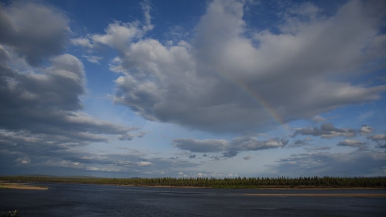 A rainbow is seen over a river.