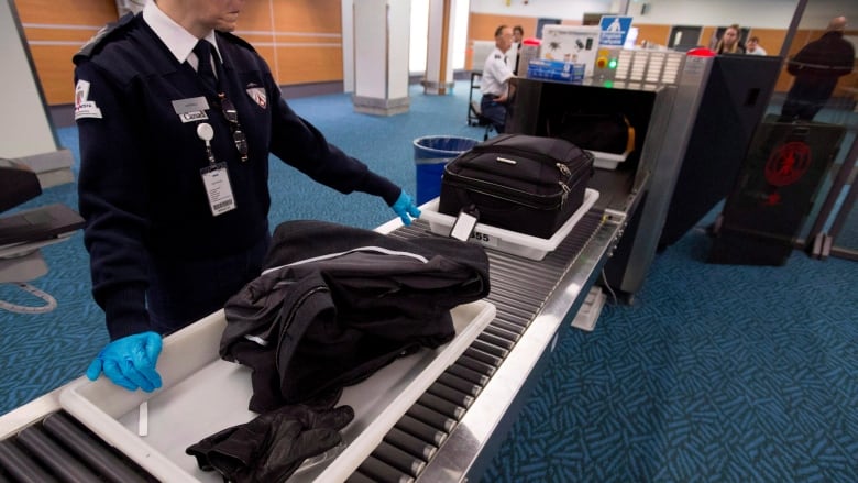 A screening officer at the airport looks at carry on bags.