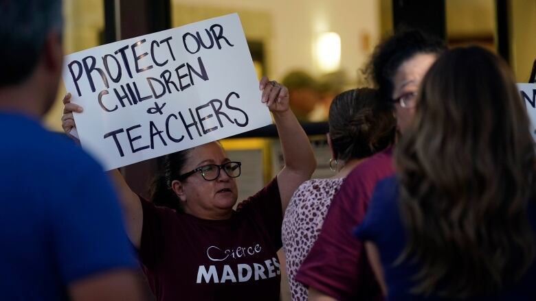 A woman at a protest holds up a placard.