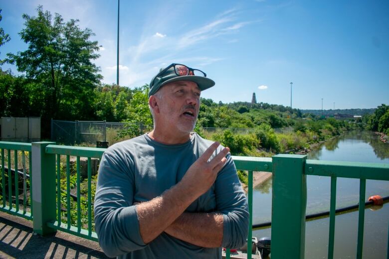 A man stands on a bridge above water