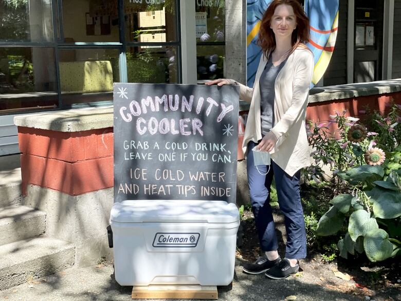 A woman standing in front of a cooler marked 'Community Cooler.'