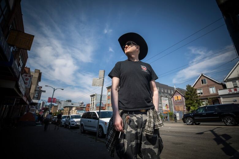 Garth Mullins looks away from the camera. He is wearing a wide-brimmed hat and a black shirt with the Vancouver Area Network of Drug Users logo.