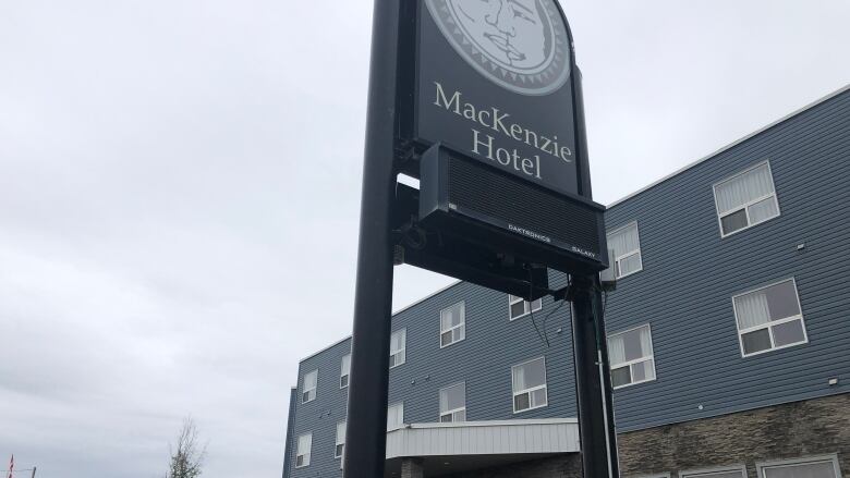 A sign looms over a blue building.