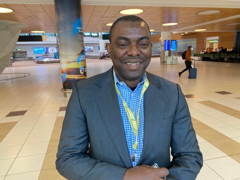 Smiling man stands in arrivals area of Winnipeg airport.