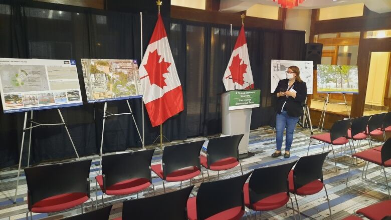 Press release staging of a podium in front of two Canadian flags and four project plot placards. Empty chairs are pointed towards the podium and a reporter is looking at some of the placards.