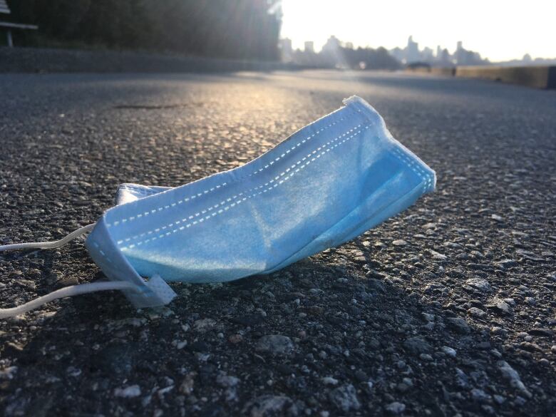 A blue face mask lies on a street.