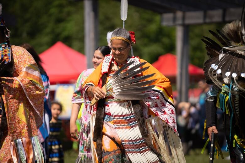 A woman dancing while wearing Indigenous regalia.