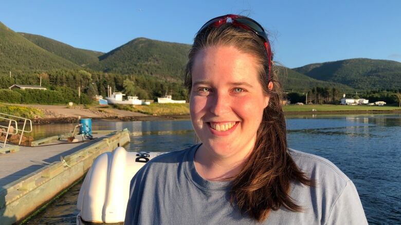 A white woman is seen wearing dark hair in a ponytail and a t shirt with a grey whale on it. 