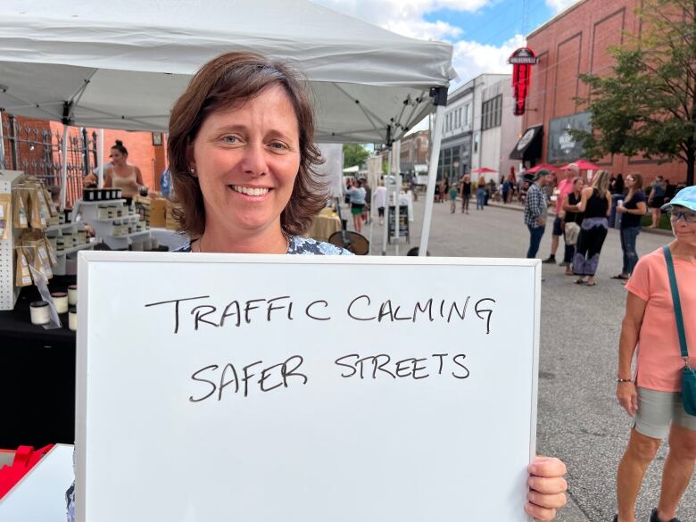 A woman holding up a small whiteboard that says 