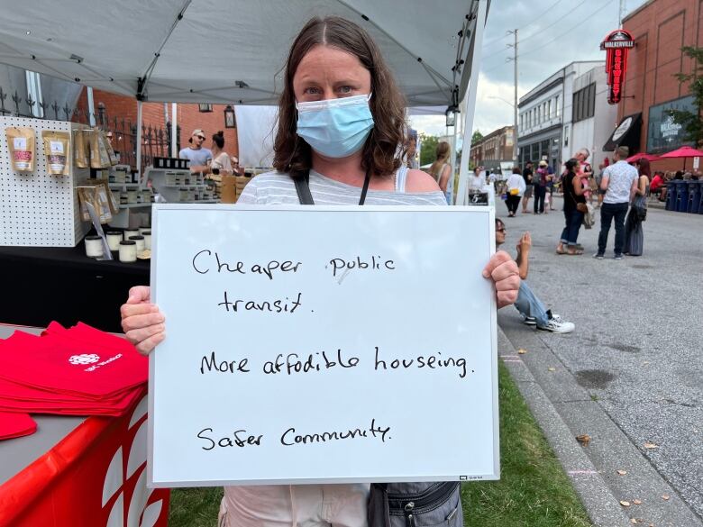 A woman holds a small whiteboard that says 