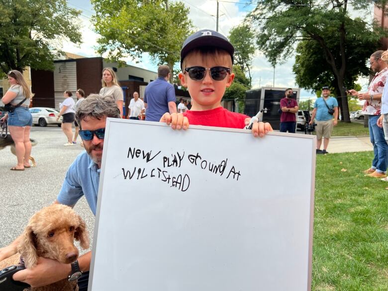 A boy holding a whiteboard that says 