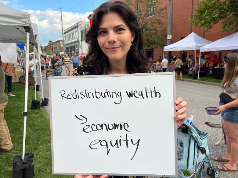 A woman holds a whiteboard that says 