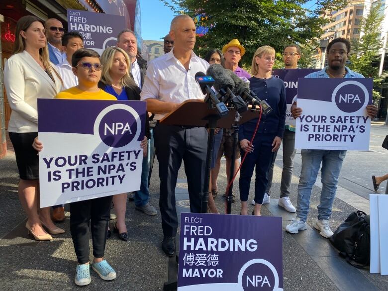 Fred Harding stands at a podium, flanked by supporters and NPA signs.