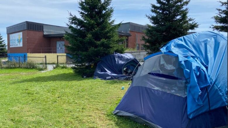 Tents sit on the grass behind a school