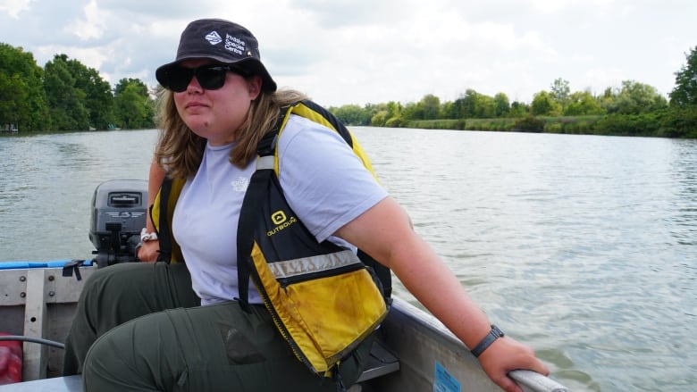 Woman wearing lifejacket cruises the Welland River, looking for invasive European water chestnut