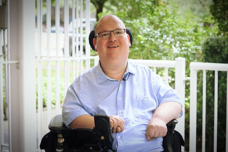 A bald man smiles from a wheelchair.