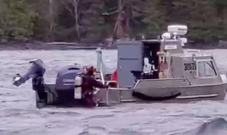 A grainy video still shows a diver climbing up to a small boat.