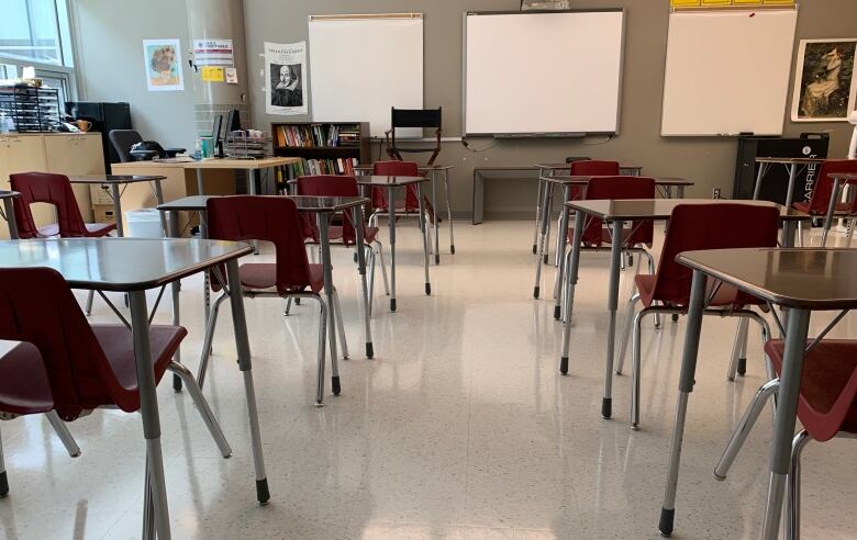 Desks and red plastic chairs in a classroom.