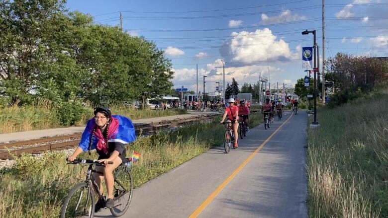 People cycle along a paved trail.