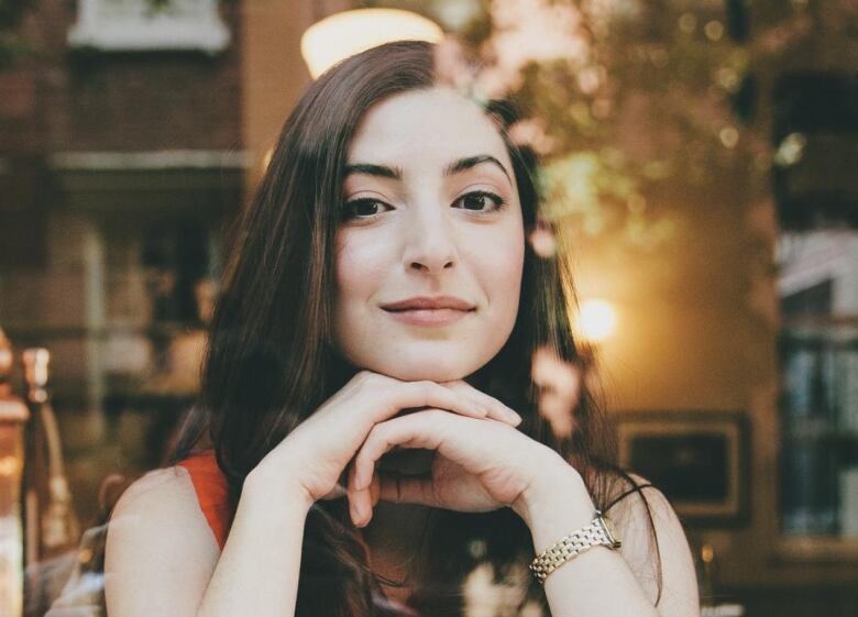 A woman sits behind a glass window.