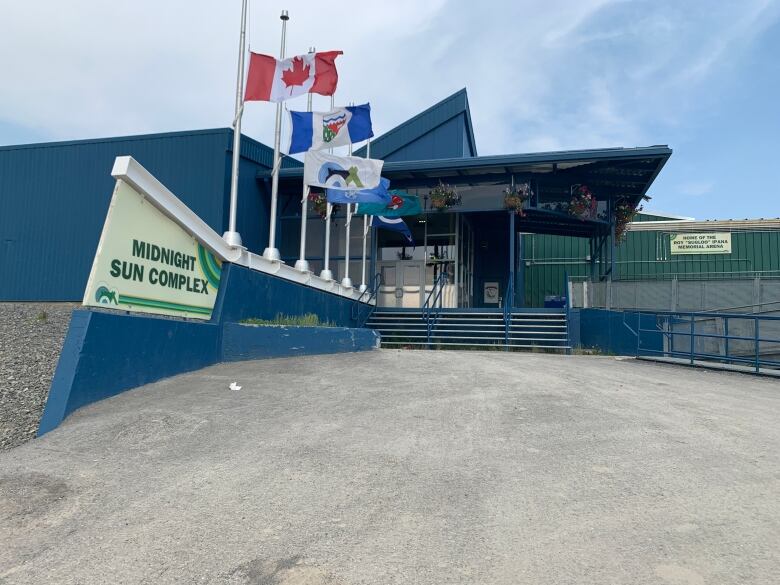 A dusty, dark blue building with flags and a sign. 