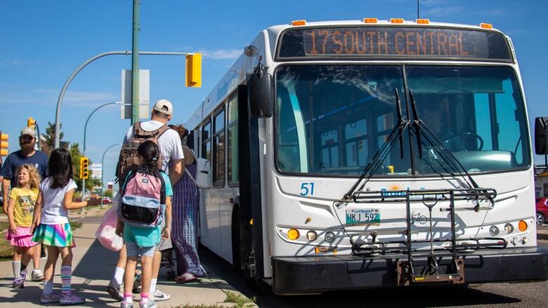 A group of people line up to get on a bus.