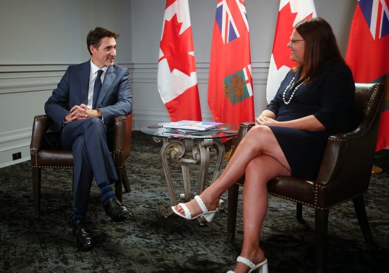 A man and a woman are seated beside each other in separate chairs.