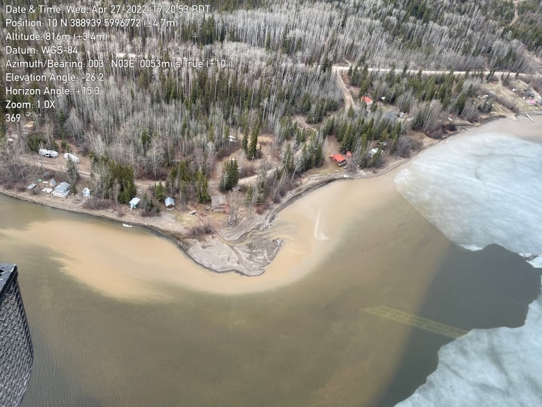 An aerial shot shows an icy river with brown sediment in it.