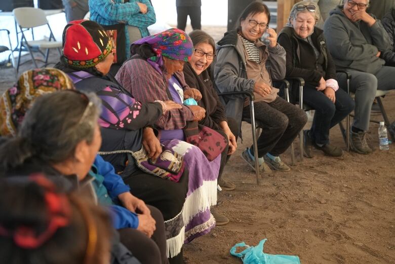 Innu women sit in a circle, playing a game of pass the package.