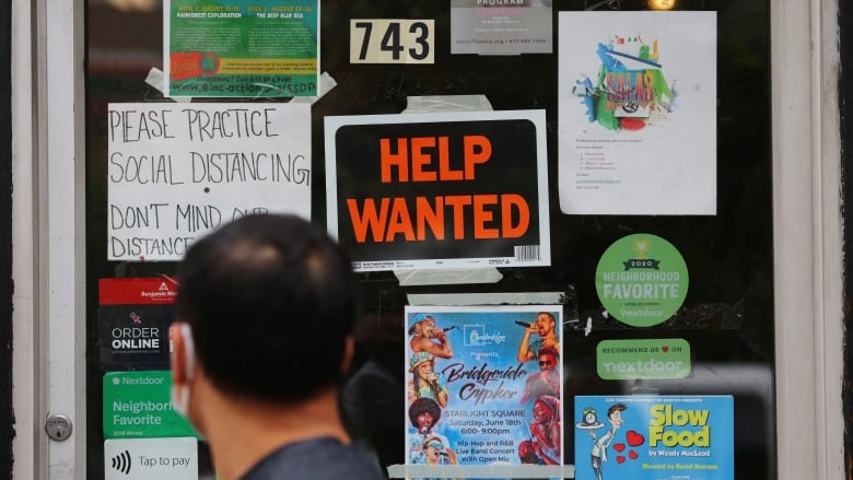 A person walks in front of a door which has signs reading 