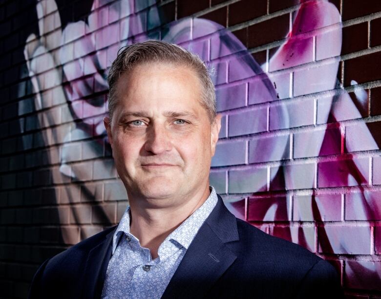 man stands in front of wall with graffiti art on it.