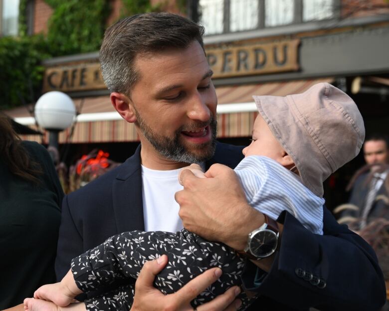 A smiling fathers holds his baby. 