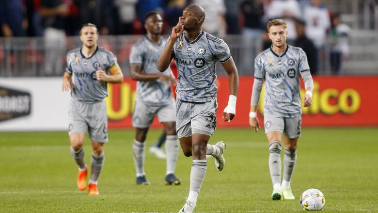 Several professional soccer players trot across the field.