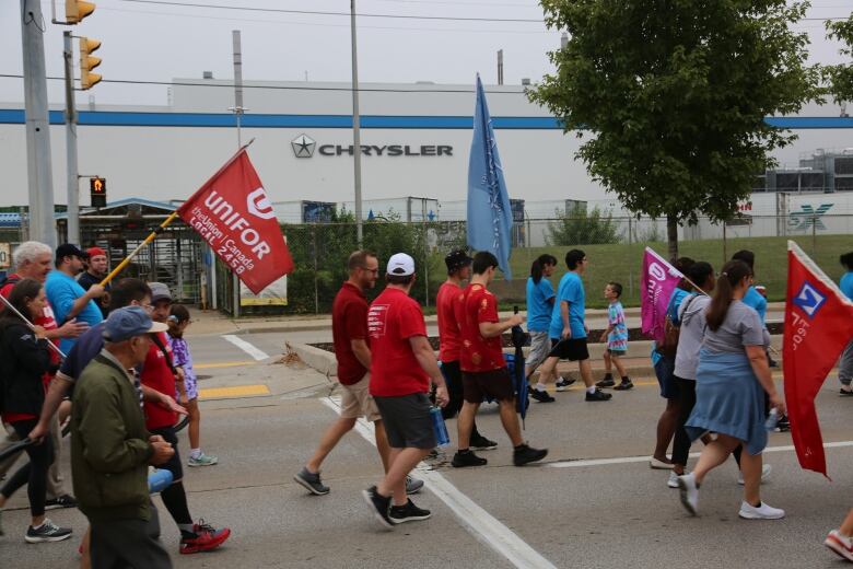 Union workers marching in a parade outside a car manufacturing factory