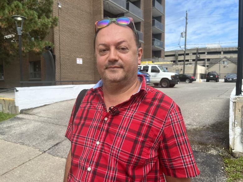 A man wearing a red shirt and sunglasses on his head