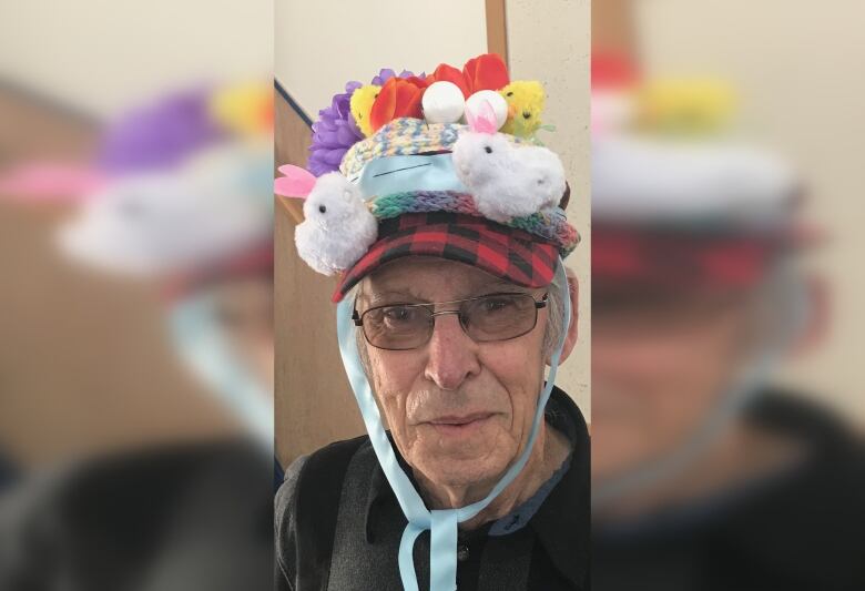 An elderly man wearing a hat with colourful flowers and animals