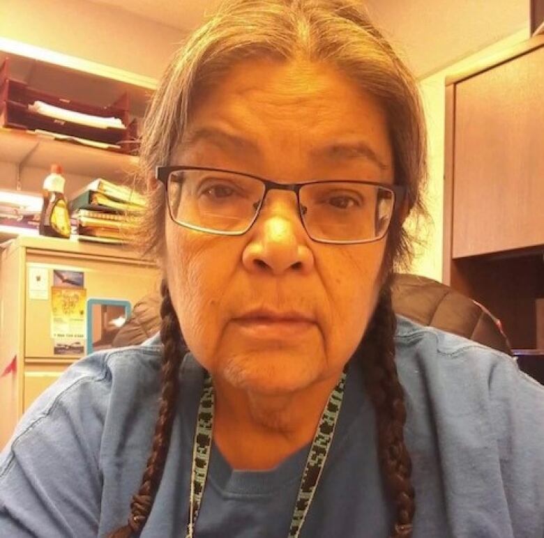 Woman with braided hair and blue shirt sitting in chair