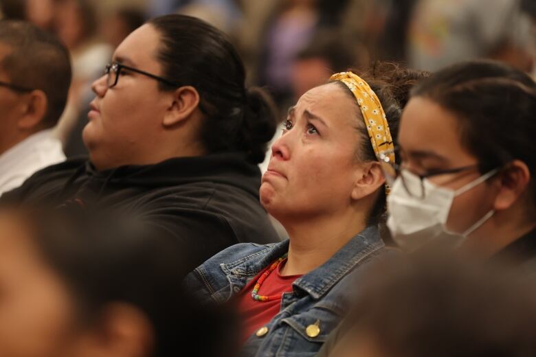 A woman appears to tear up while seated in an audience. 