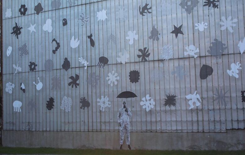 Picture of a mural that shows toxic particles and a man in a hazmat suit holding an umbrella.