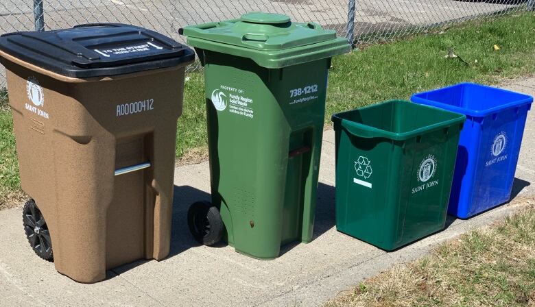 A collection of different coloured bins on the sidewalk.