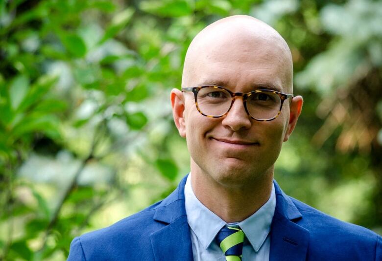 A bald man with glasses in a suit and tie.