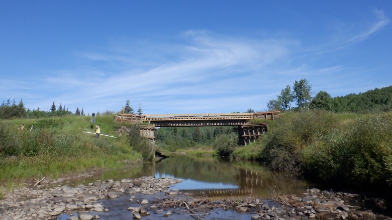 A river with very low water levels is seen, with a bridge in the background.