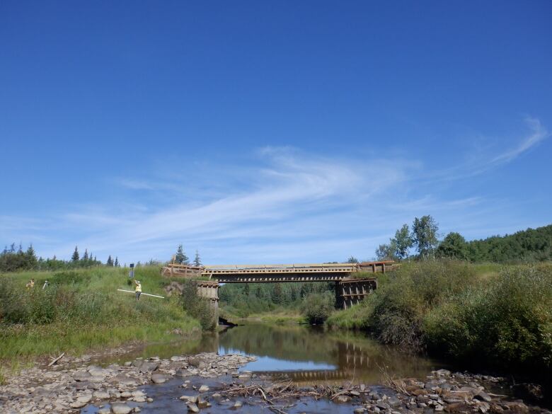 A river with very low water levels is seen, with a bridge in the background.