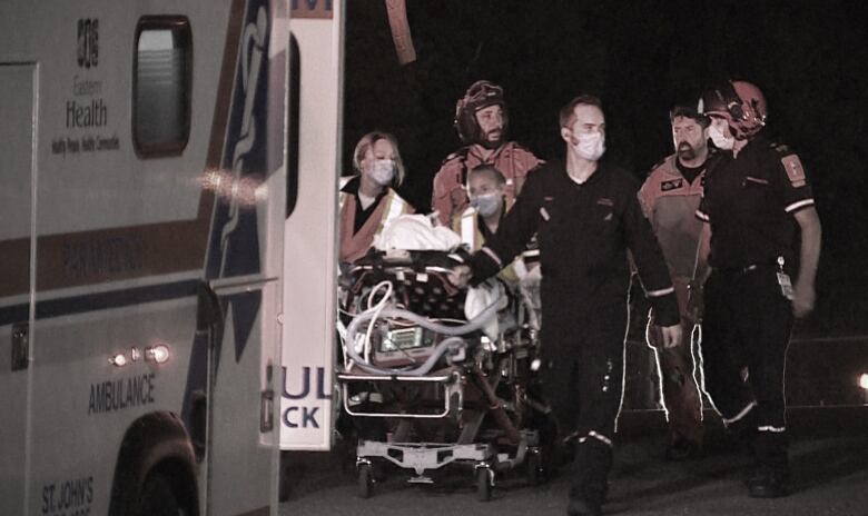 Paramedics wheel a stretcher carrying an injured worker.